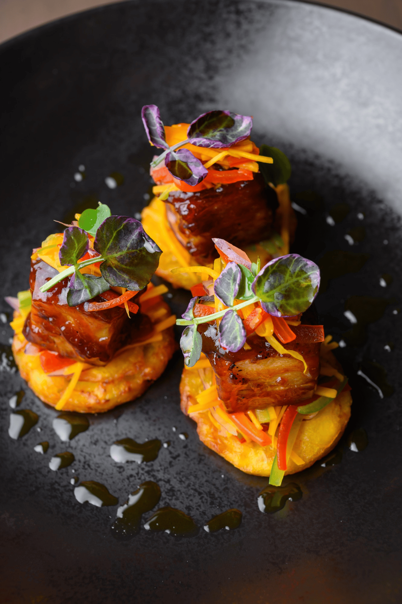 Plated gourmet appetizer with glazed pork and microgreens